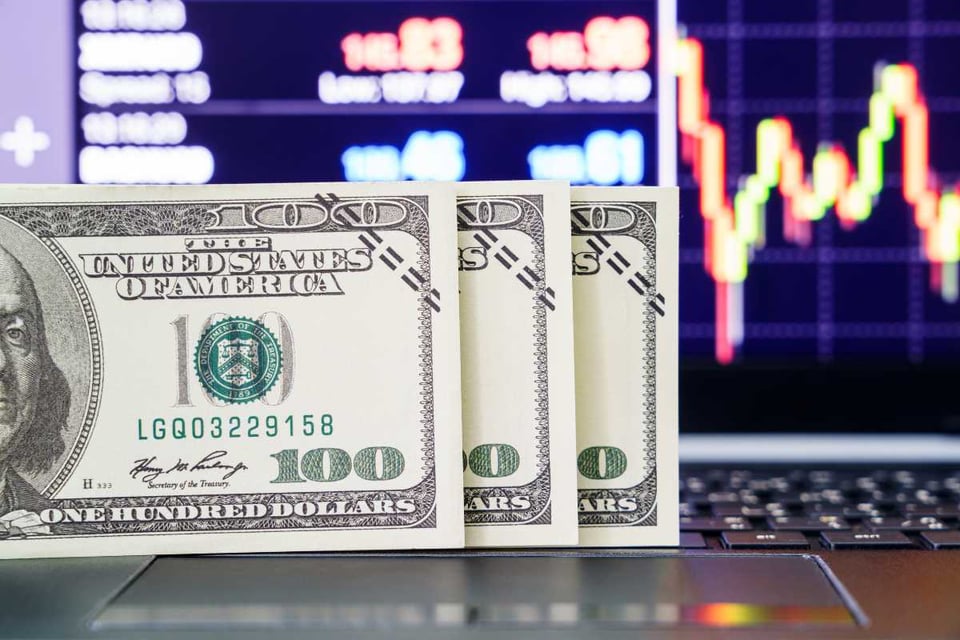 billetes de 100 dólares y pantalla de computadora con graficos