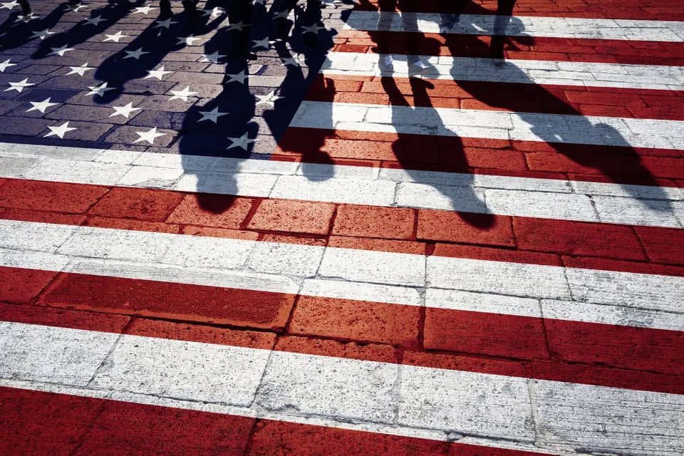 sombra de personas sobre bandera pintada en suelo, inmigrates en eeuu