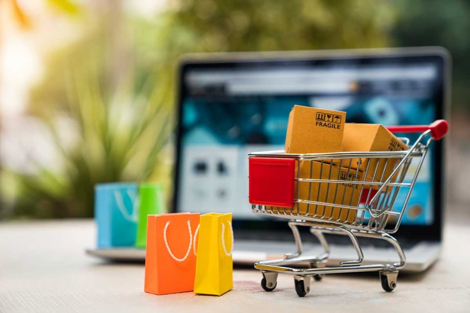 figura de carrito de compras con algunas bolsas coloridas
