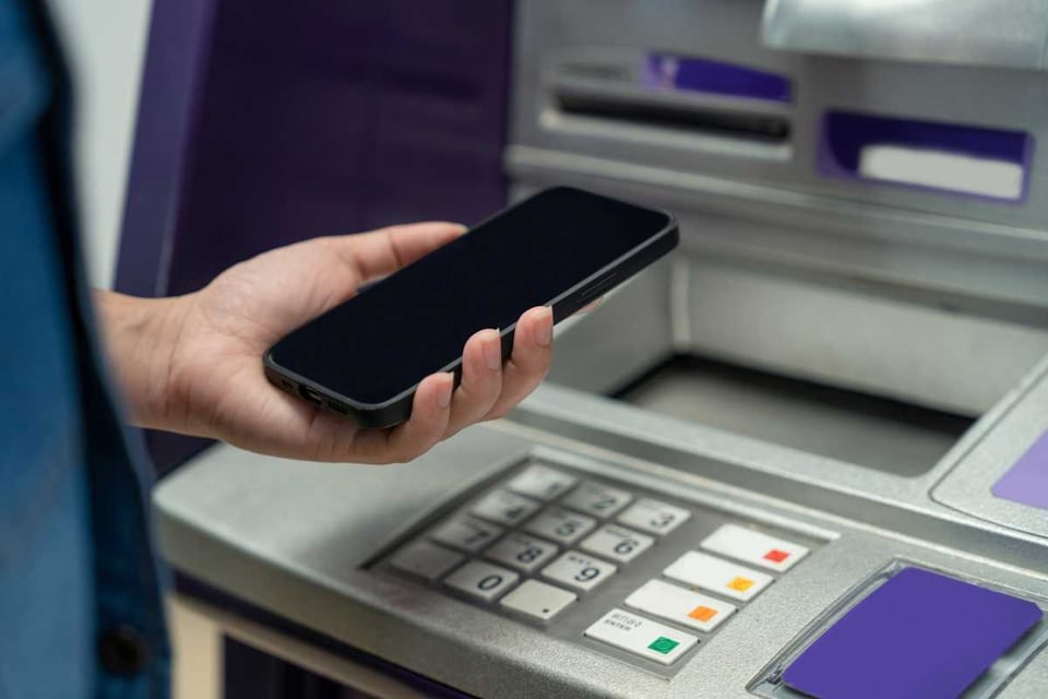 persona con telefono en un cajero de banco