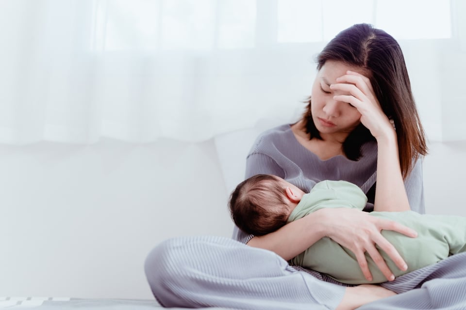 Tired woman carrying baby, MundoNow