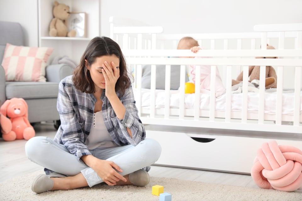 Woman with postpartum depression, baby in the cradle, MundoNow