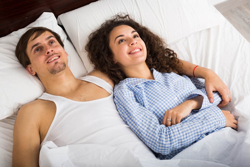 Happy man and woman lying in bed, smile