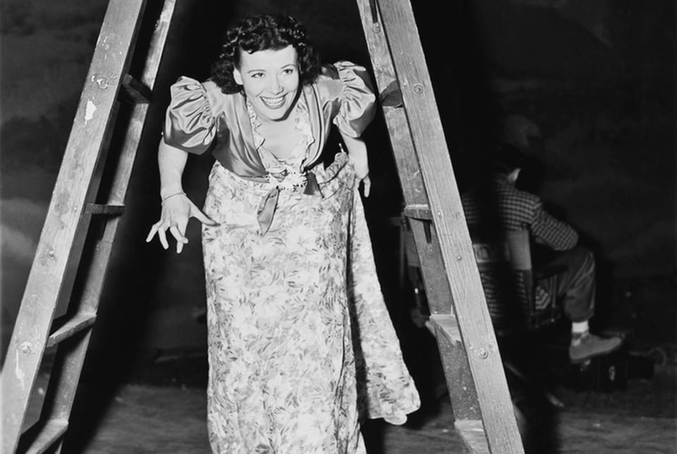 Woman walking under a step ladder, fingers crossed