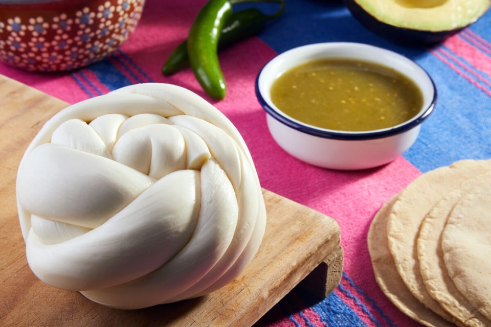 Queso Oaxaca en tabla junto con salsa y chile