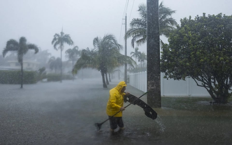 hombre con impermeable amarillo, palmeras, diluvio, Miami, MundoNOW