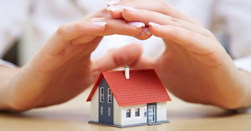 Concept of first house with a tiny one protected by hands