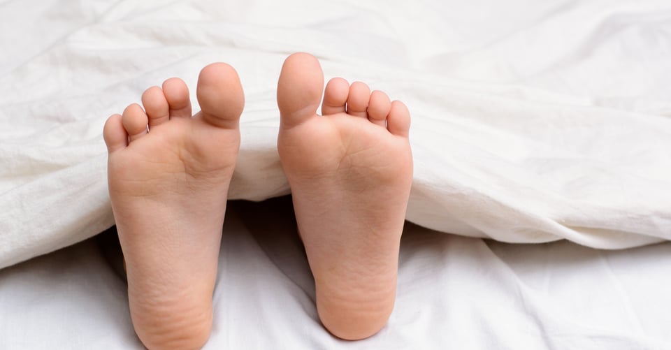 Pies de alguien descalzo en cama