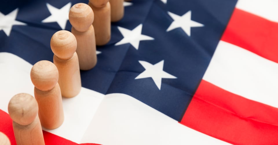 Muñecos de madera en bandera de EEUU como idea de inmigración