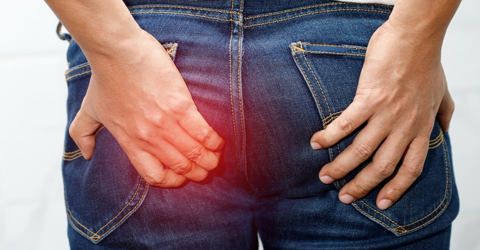Persona sujetando glúteos con dolor rectal