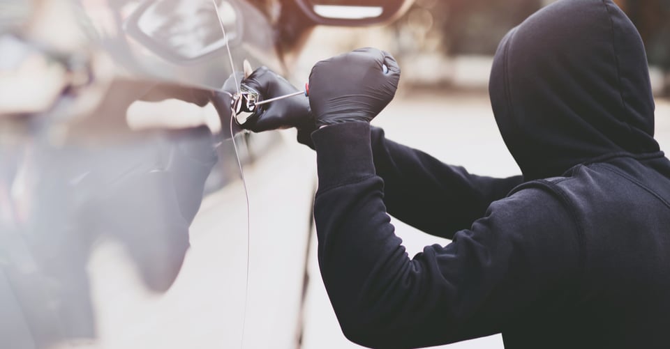 Un ladrón tratando de entran a un auto