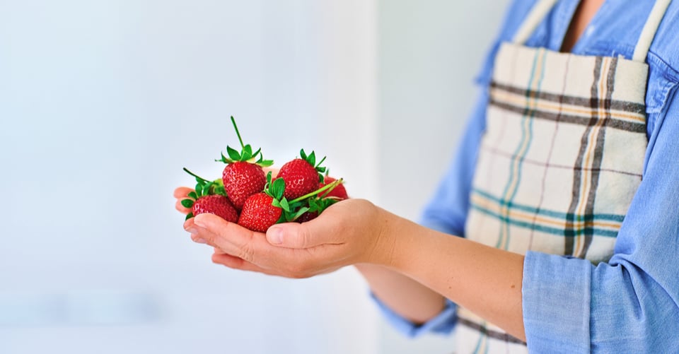 Una persona agarrando fresas, que son agradables para riñones