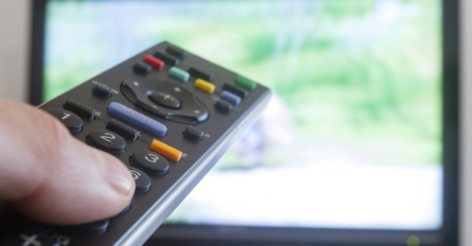 Un control apuntando a la tele que transmite estrenos