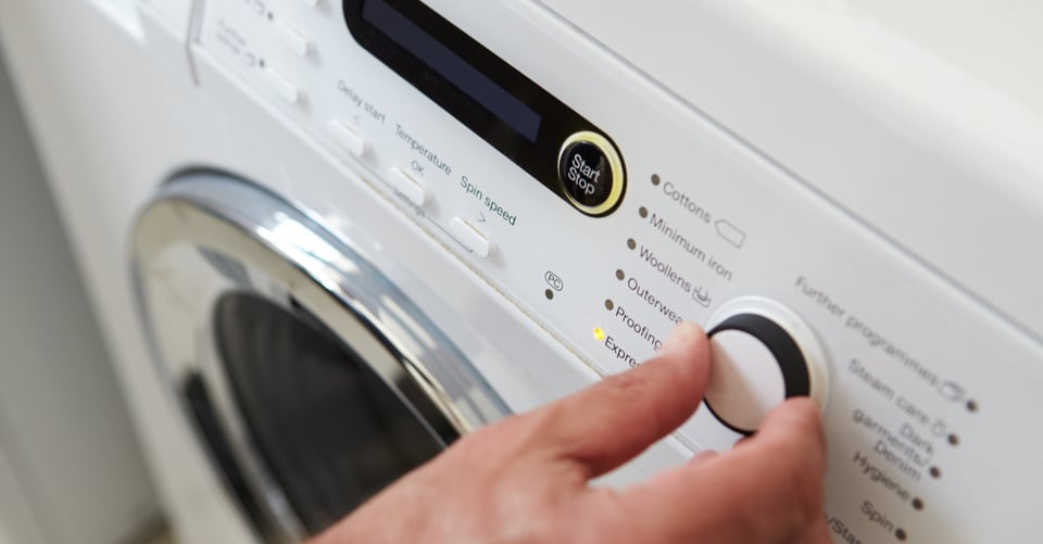 Persona usando lavadora para lavar prendas o algo como sábanas