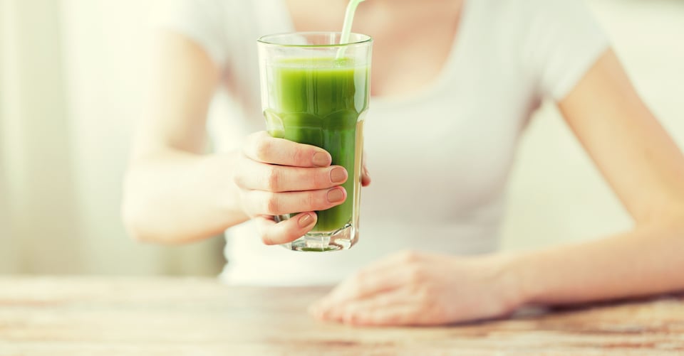 Un vaso con jugo siendo sostenido por mujer