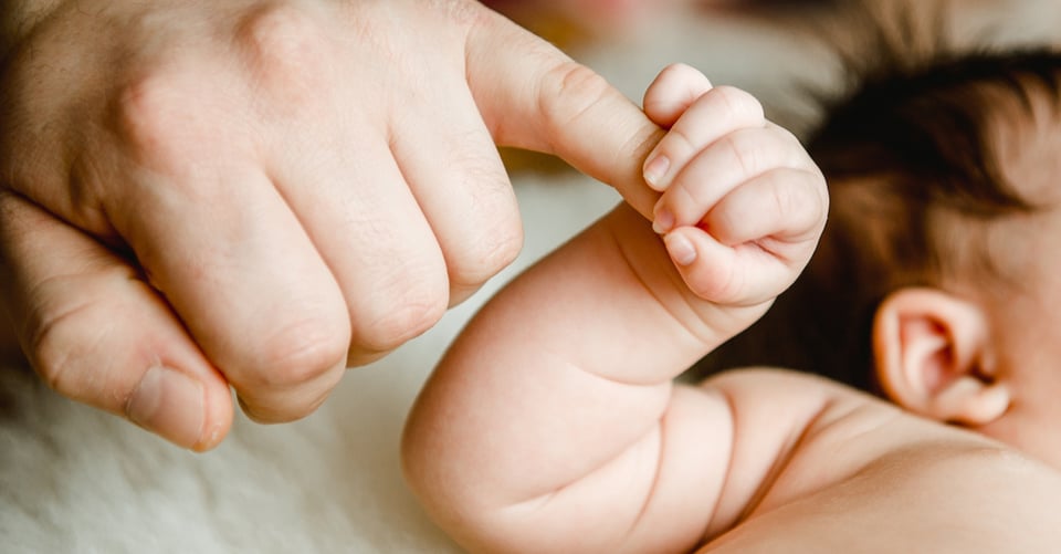 Dad's hand being held by his baby