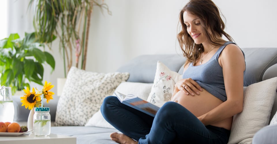 A pregnant woman sitting reading a book