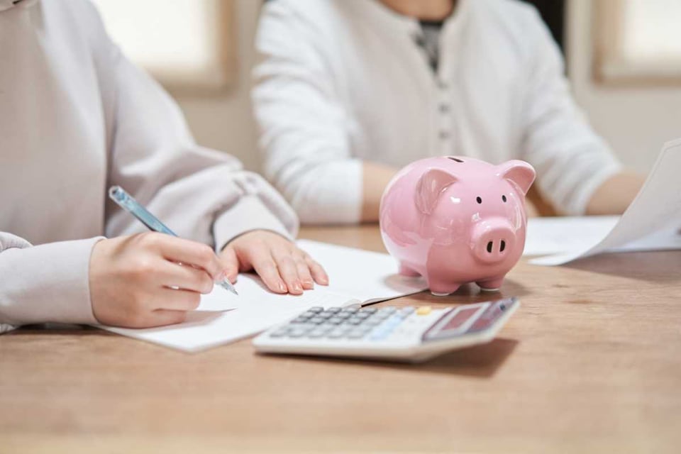 dos personas haciendo cáculos y escribiendo en papel, planes de ahorro