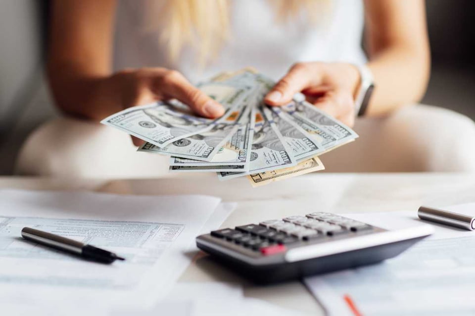 persona con billetes en la mano y calculadora en una mesa, Purchasing Power Falls in the US