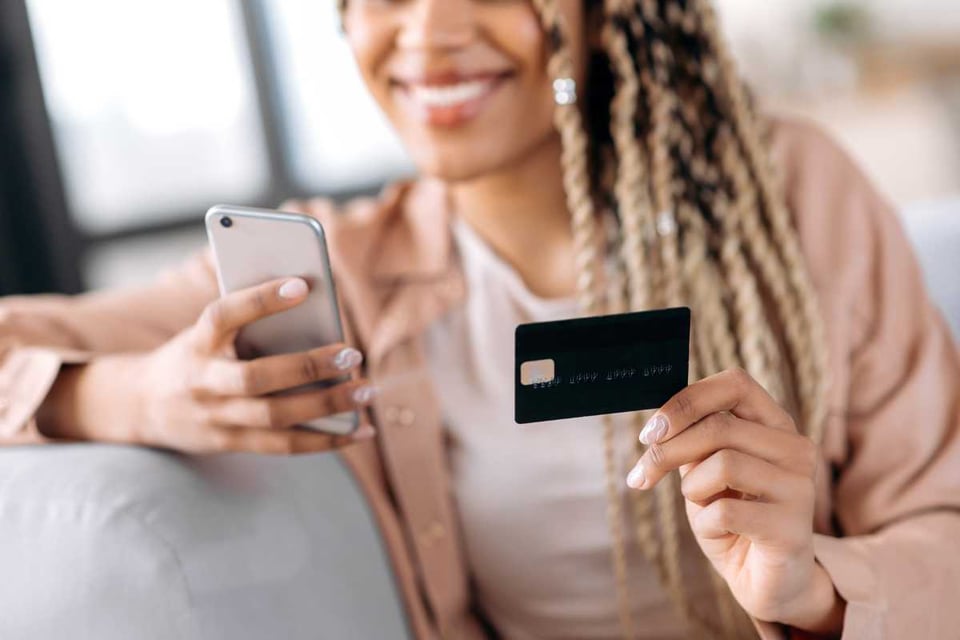 mujer con teléfono y tarjeta haciendo compras online
