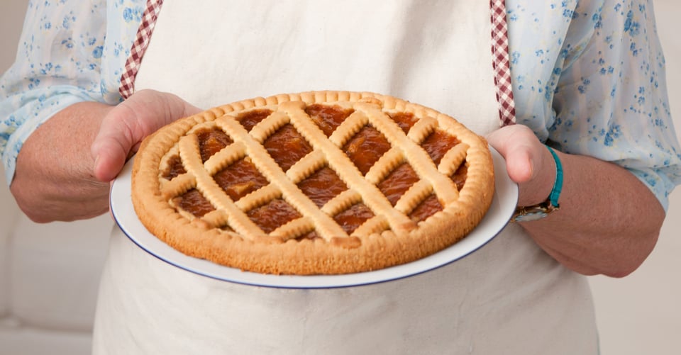 Happy smiling elderly woman showing her apricot tart