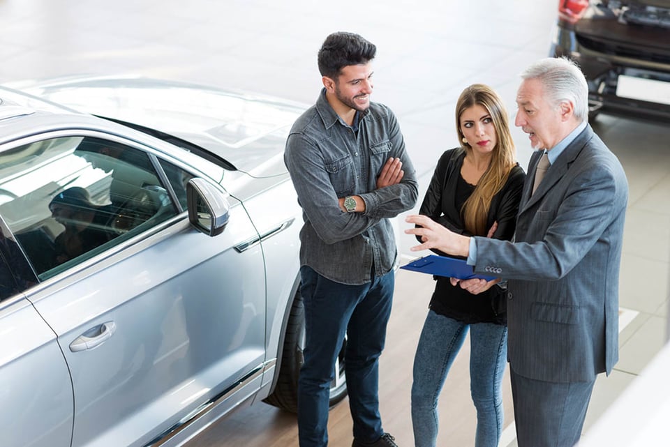 Happy young family talking to the salesman, showroom