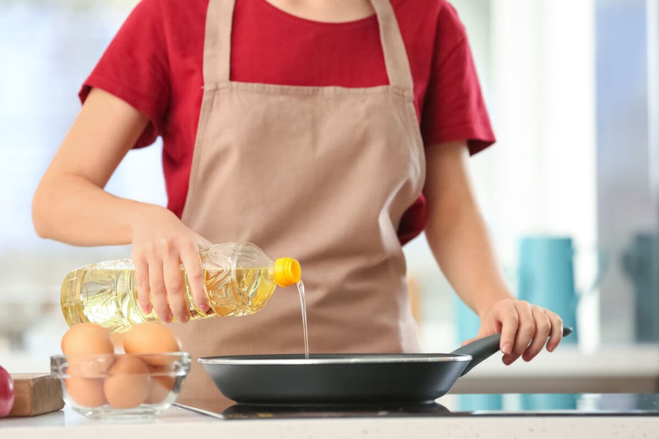 Mujer cocinando con aceite saludable para alimentos