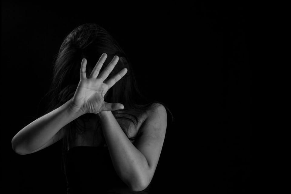 A woman in black and white covering her face as an example of a case of violence