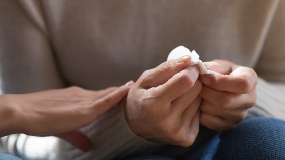 Manos con pañuelo con lágrimas como idea de tristeza por desaparición de un ser