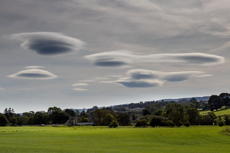 A couple of clouds with UFO form on a field