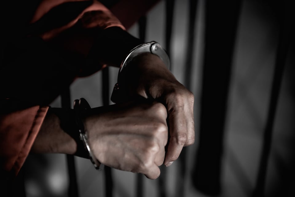 Manos de prisionero en reja