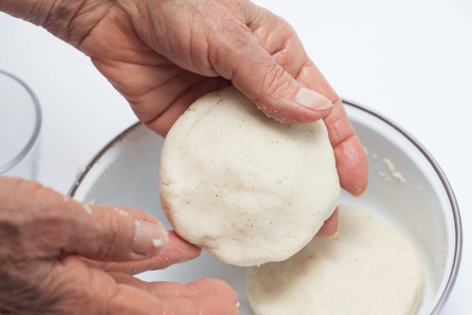 Mano haciendo arepas con masa