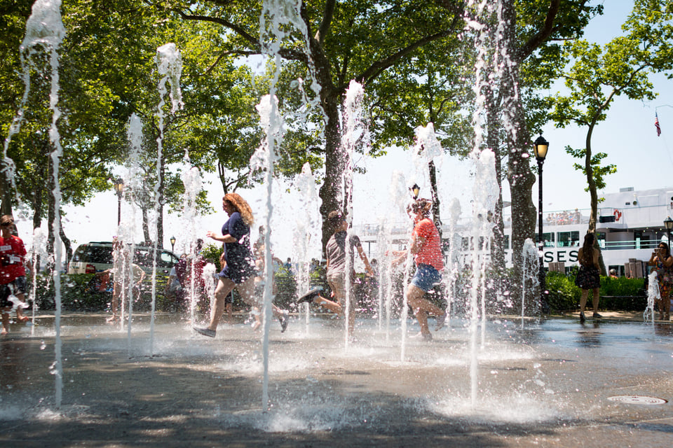 Niños divirtiéndose y refrescándose en la fuente de Battery Park en un caluroso día de verano en Nueva York