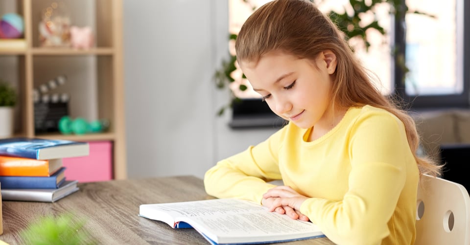 A girl reading sitting at her desk