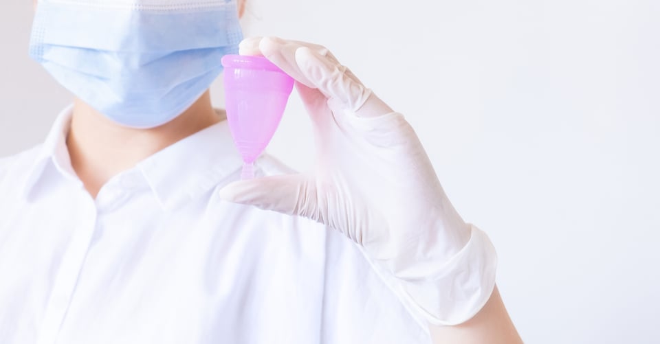Una copa menstrual en manos de una persona con guantes