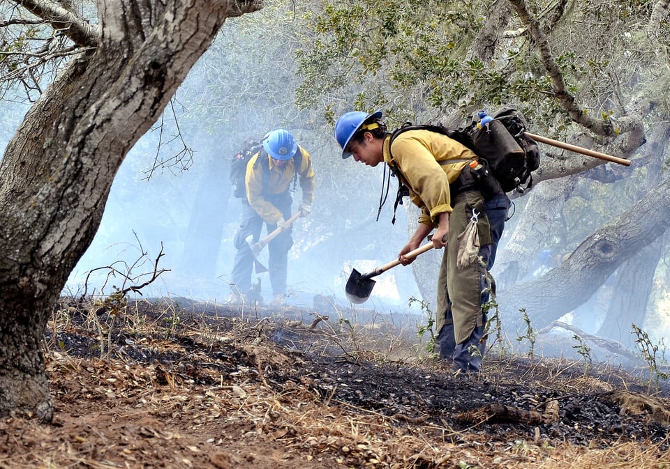 Los bomberos forestales limpian después de un incendio forestal en el condado de Santa Bárbara en California, el 5 de mayo del 2016