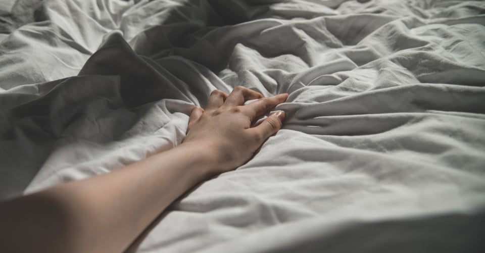 Brazo que podría ser de mujer en una cama