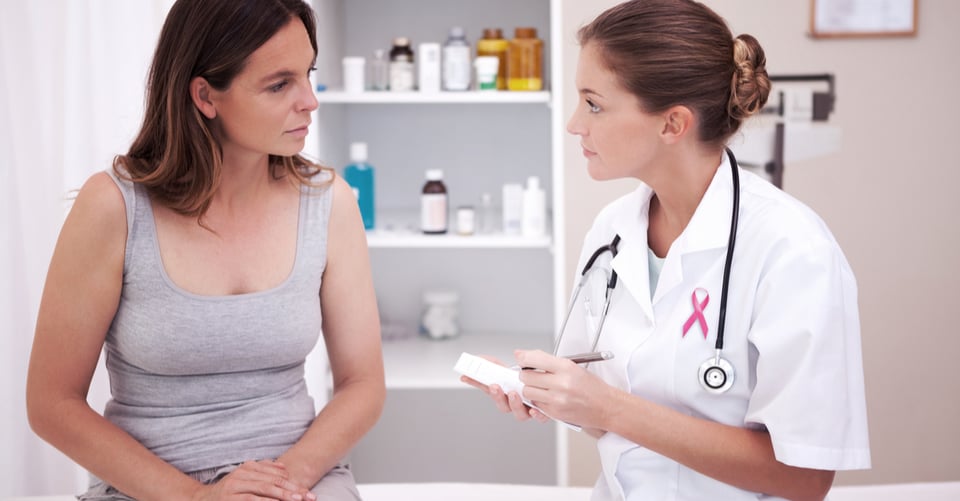 Médico con listón de cáncer de senos junto con paciente