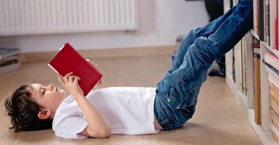 A boy reading a book on the floor