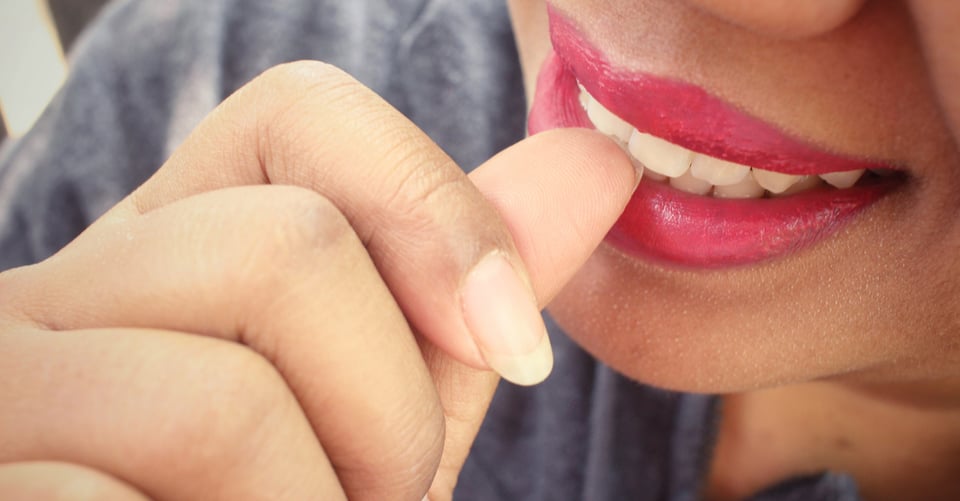 Una persona mordiendo con los dientes su dedo pulgar