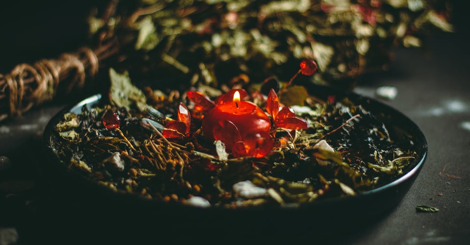 Vela en medio de un tazón con plantas como idea de amarre